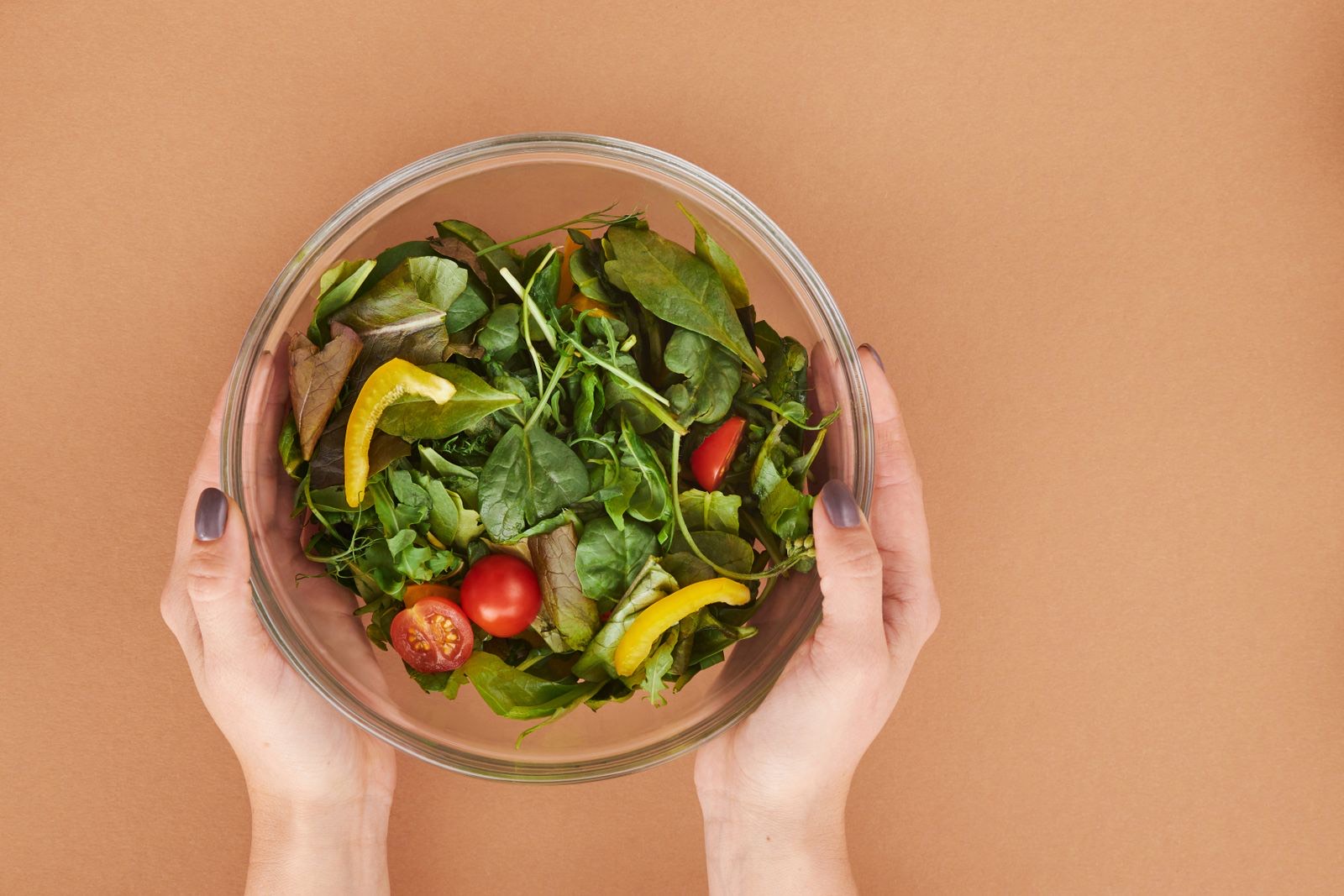 A fresh green salad with cherry tomatoes and yellow pepper in a glass bowl